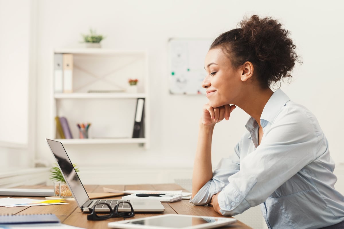 Une femme souriante à son bureau.