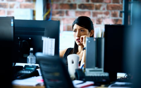 Woman using computer in an office with skeptical look on her face.