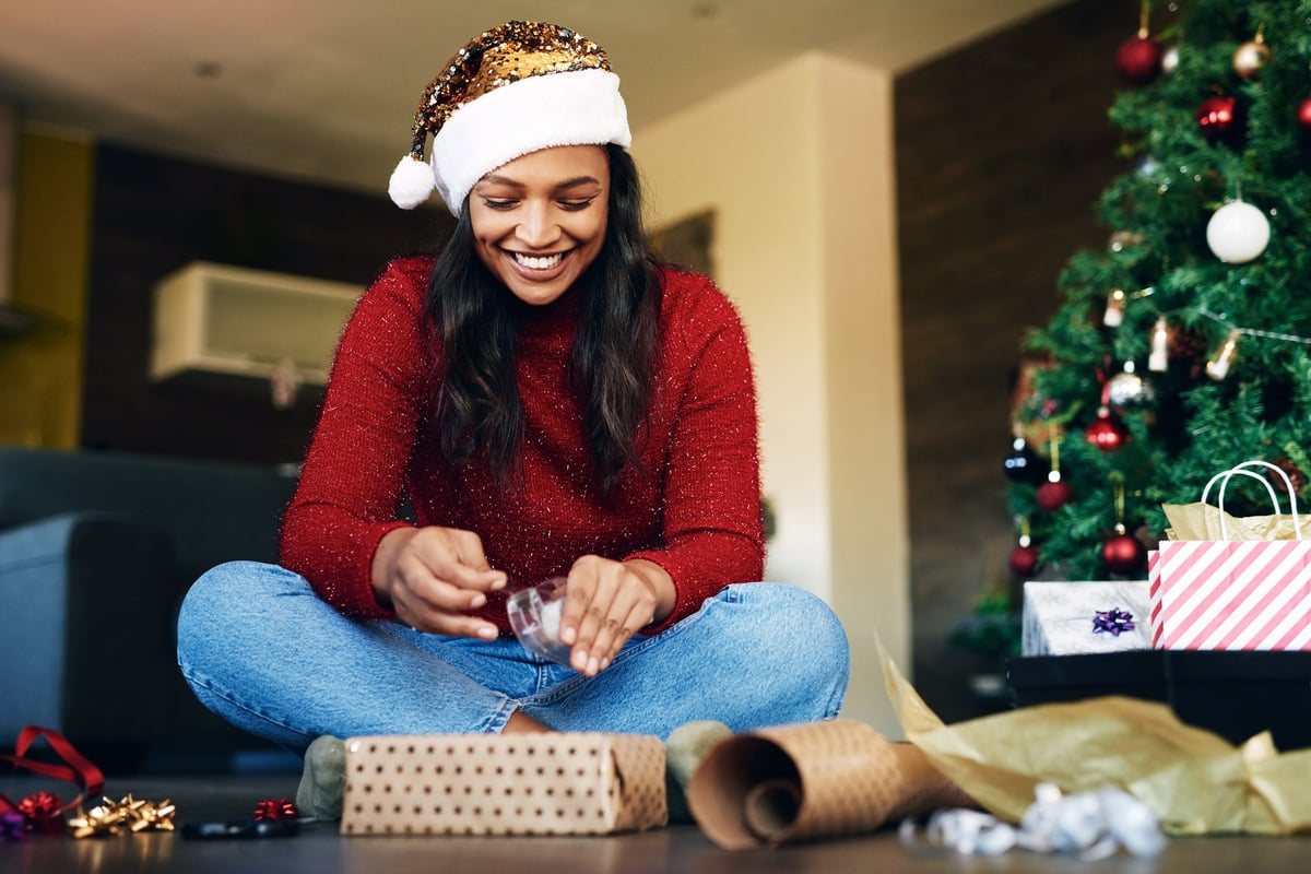 Woman wearing Santa Claus hat wrapping presents.