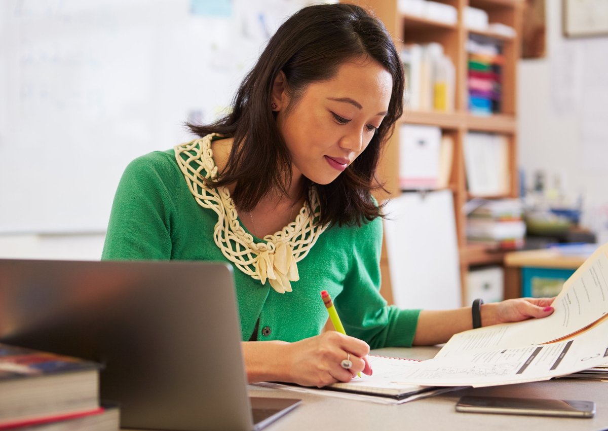 A woman reviews paperwork at her desk.