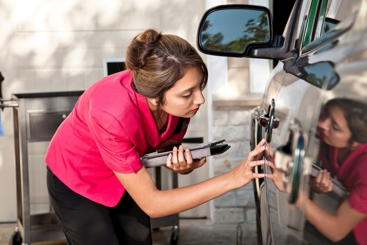 Woman with tablet inspecting vehicle damage.