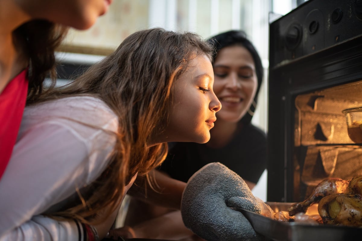 A young girl and her parents check on a turkey in the oven