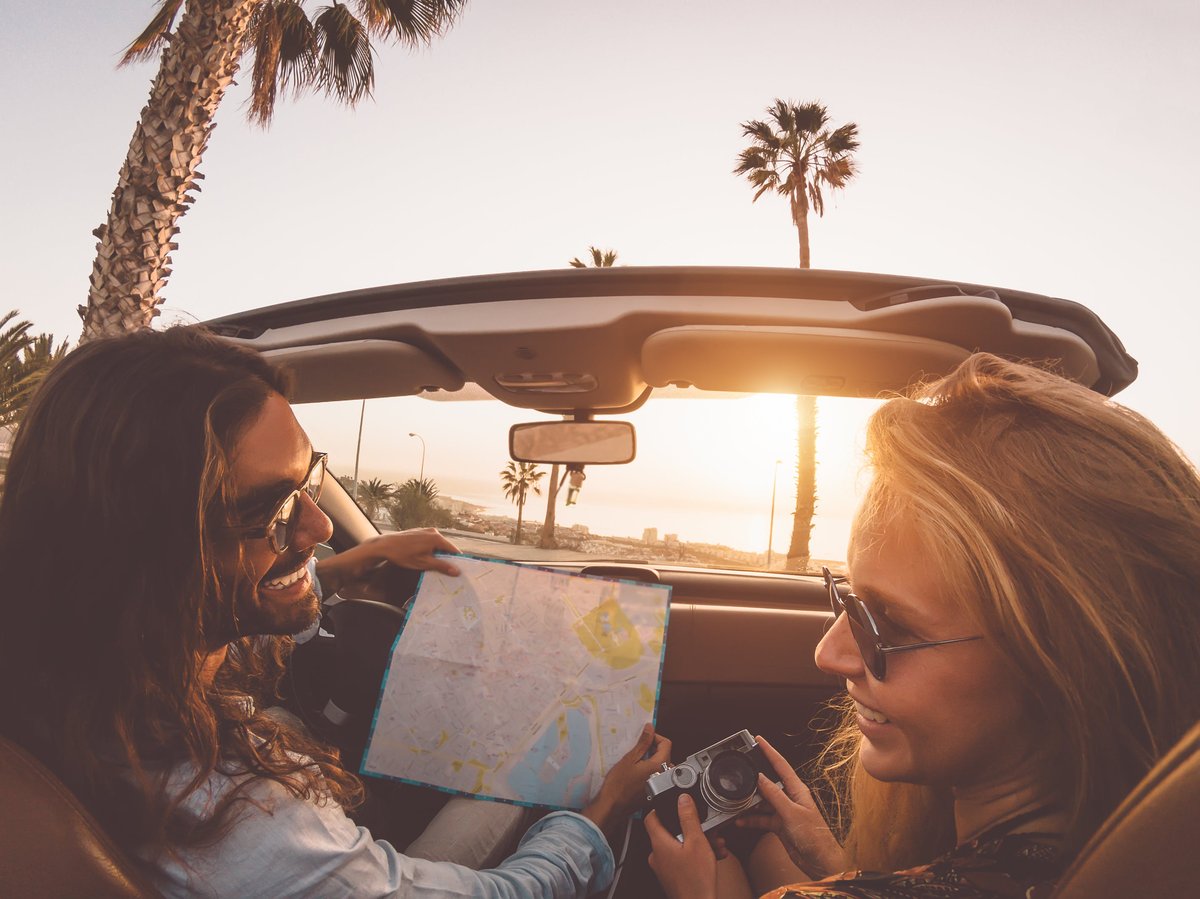 Young couple in convertible in tropical city.