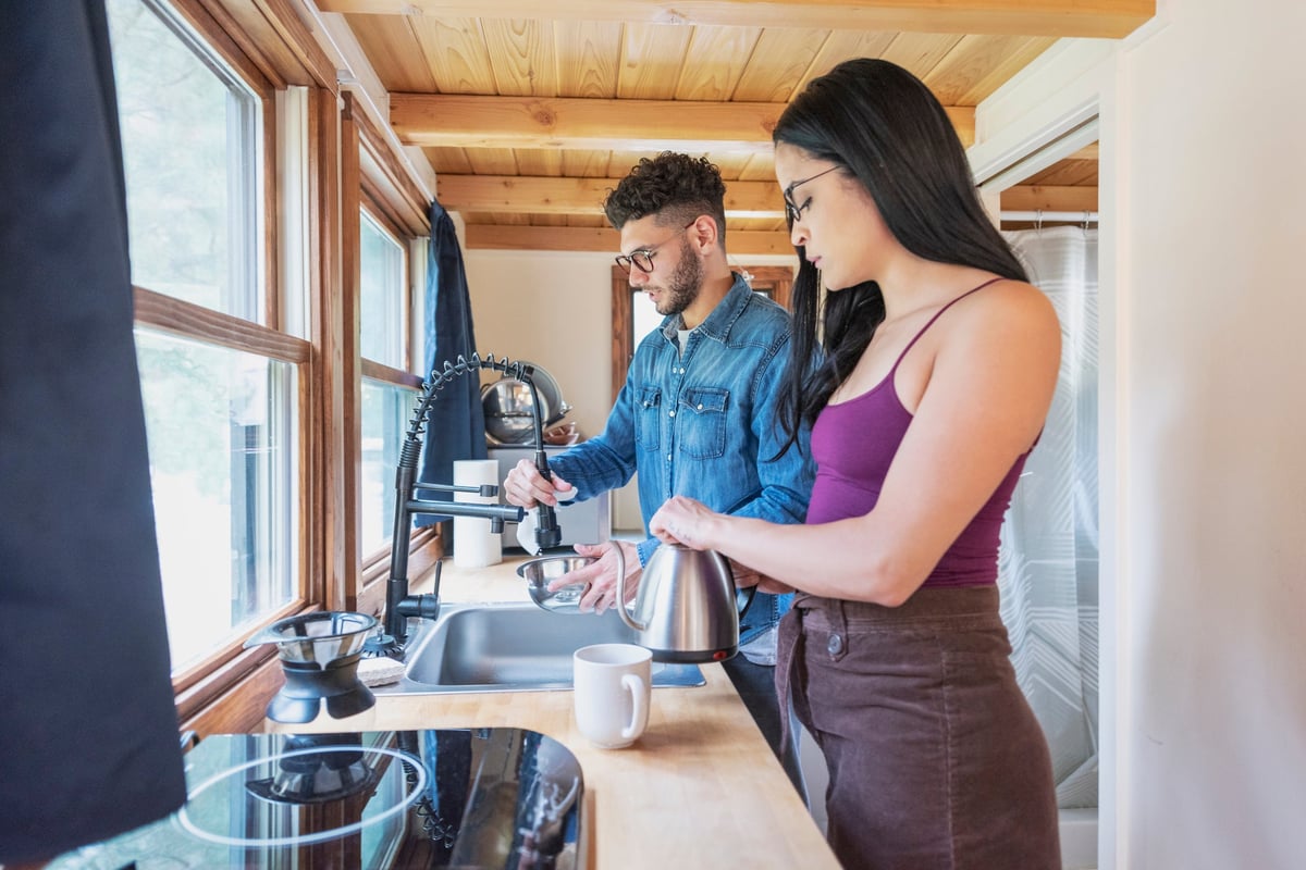 A young couple work in the kitchen of their tiny home.