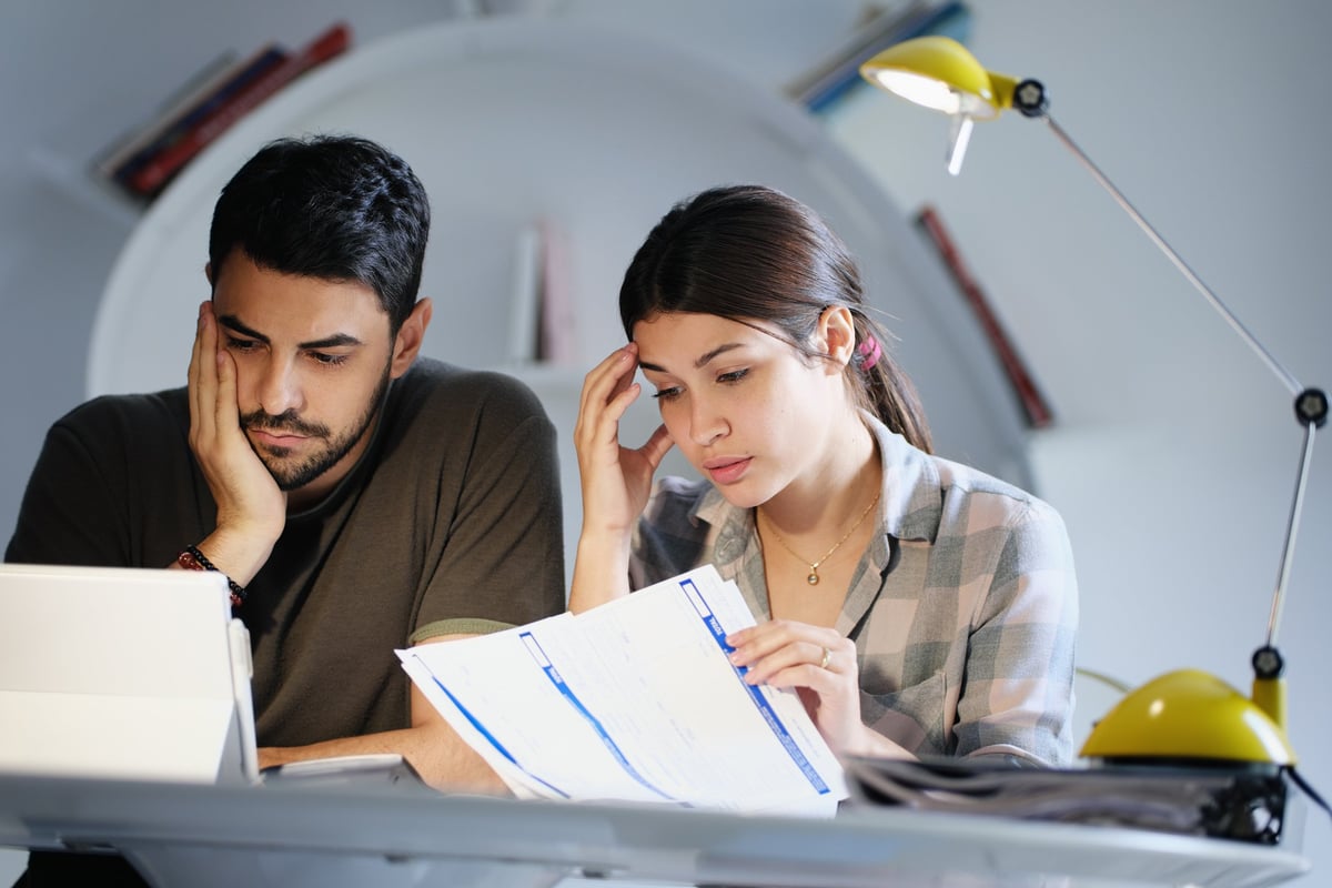 A young couple looking stressed while reviewing their bills.
