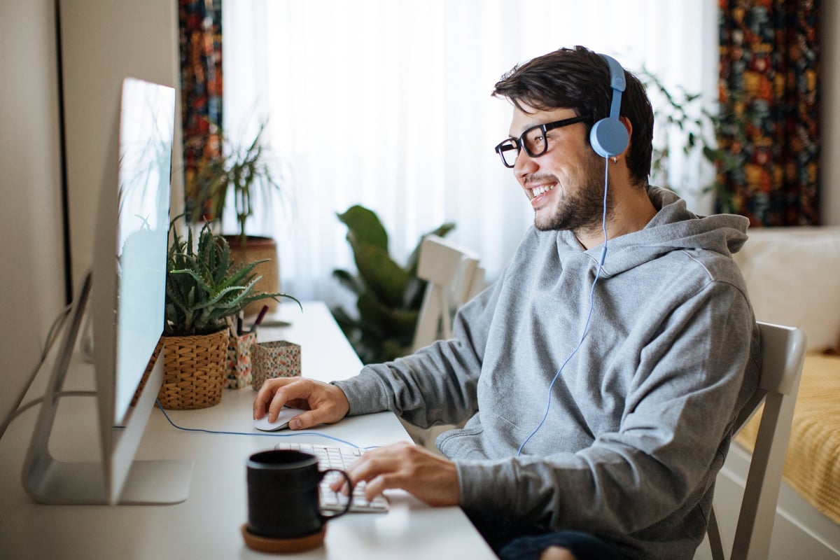 A young daytrader sits at his desk at home, looking at his computer.