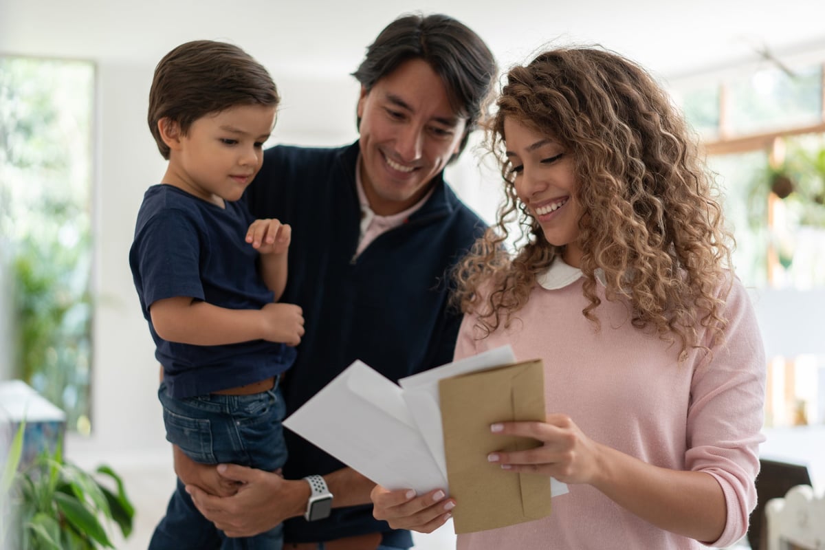 Young family smiles while looking through mail.
