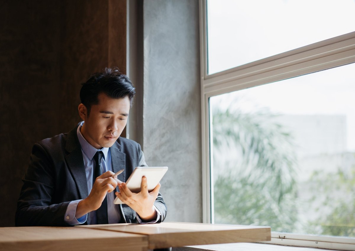 A young businessman uses his tablet to look over his investments.