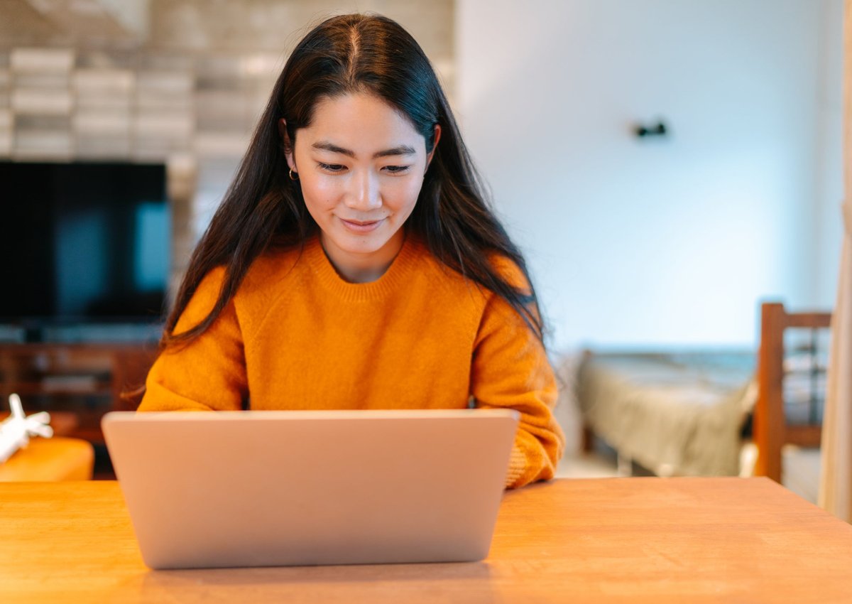 Young woman sitting at home looking at her laptop.