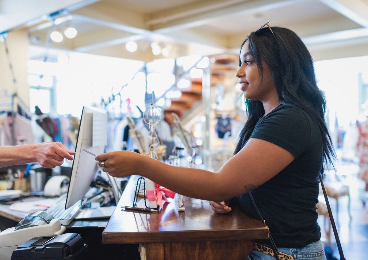 Young woman paying cashier with credit card in a clothing store