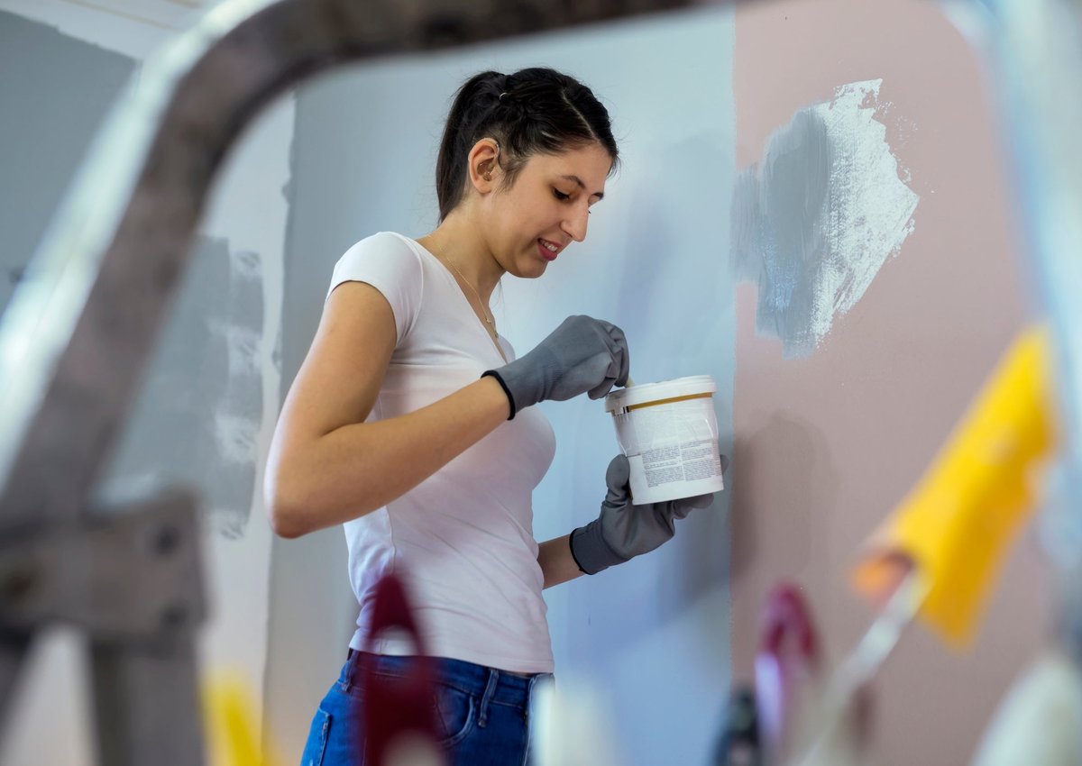 A young woman prepares to paint her walls.