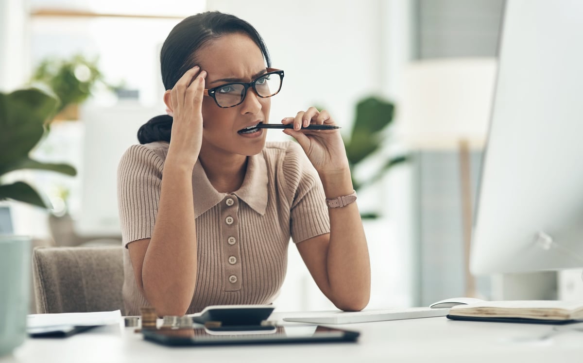 A young woman looks concerned as she reads the latest cryptocurrency news on her computer.