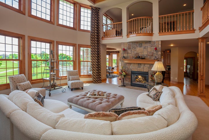 A large living room with tall windows and a big fireplace.