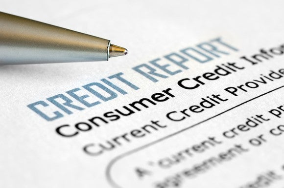 A pen lying next to a consumer credit report.