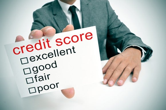 Businessman holding card that says credit score, with categories ranging from excellent to poor.