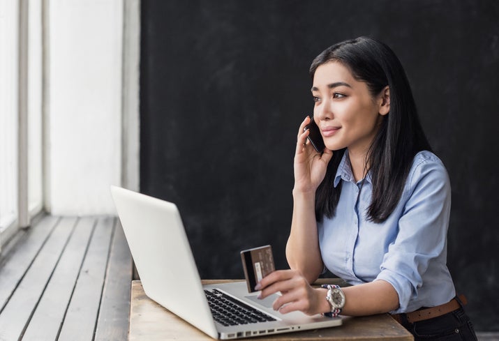 A woman on the phone with a credit card.