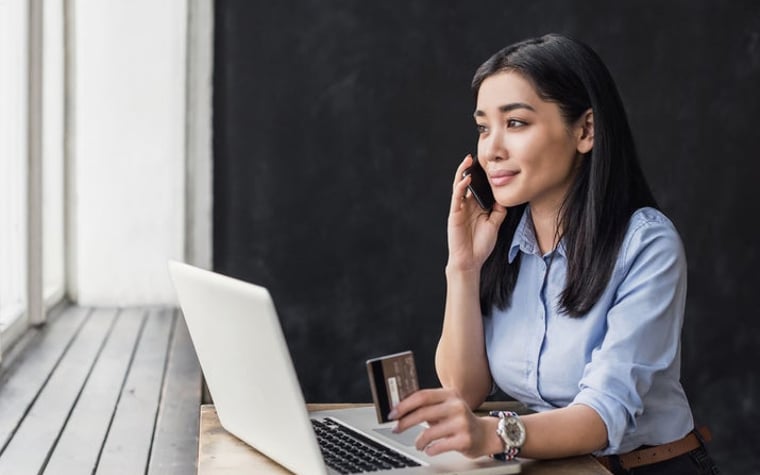 A woman is on the phone with a credit card.