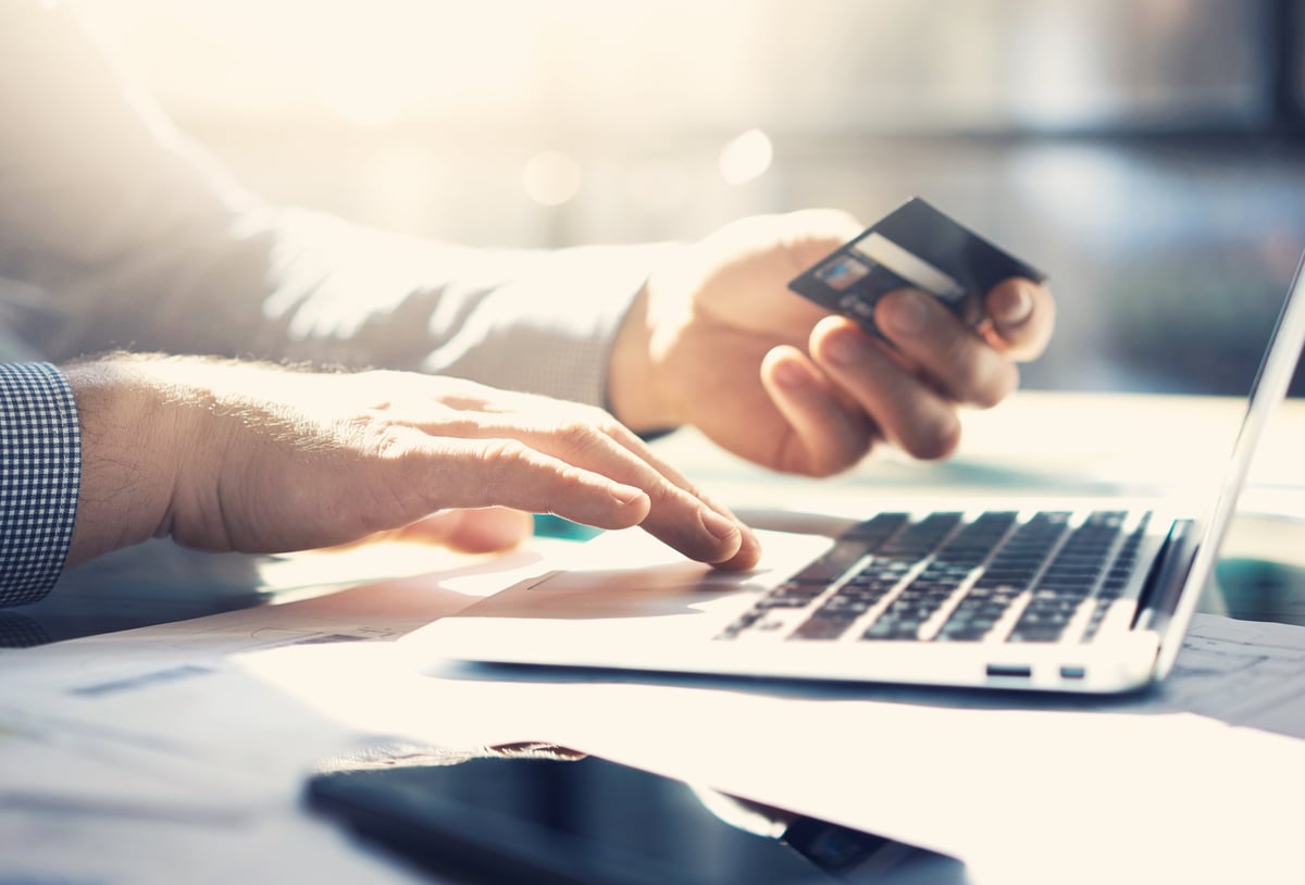 Close up of hands holding a credit card and using a laptop.