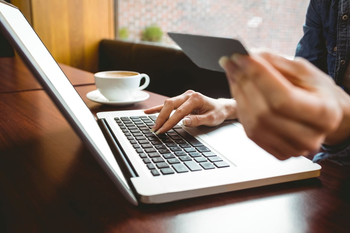 Person holding credit card and typing on laptop.