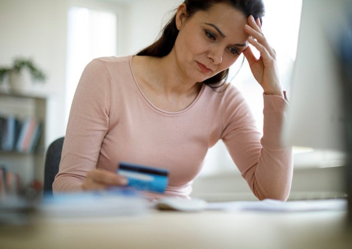 A woman with a credit card, looking worried.
