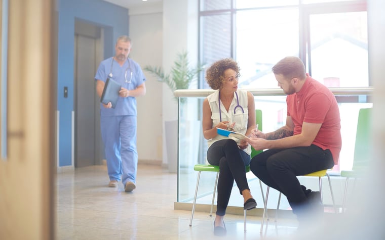 A doctor sitting in the waiting room with her patient and explaining a bill.