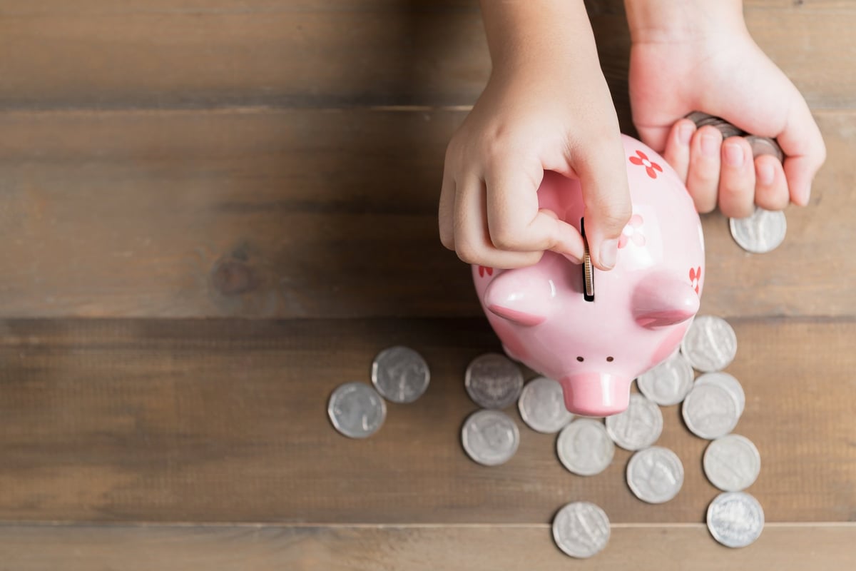 Han dropping coins into a piggy bank.