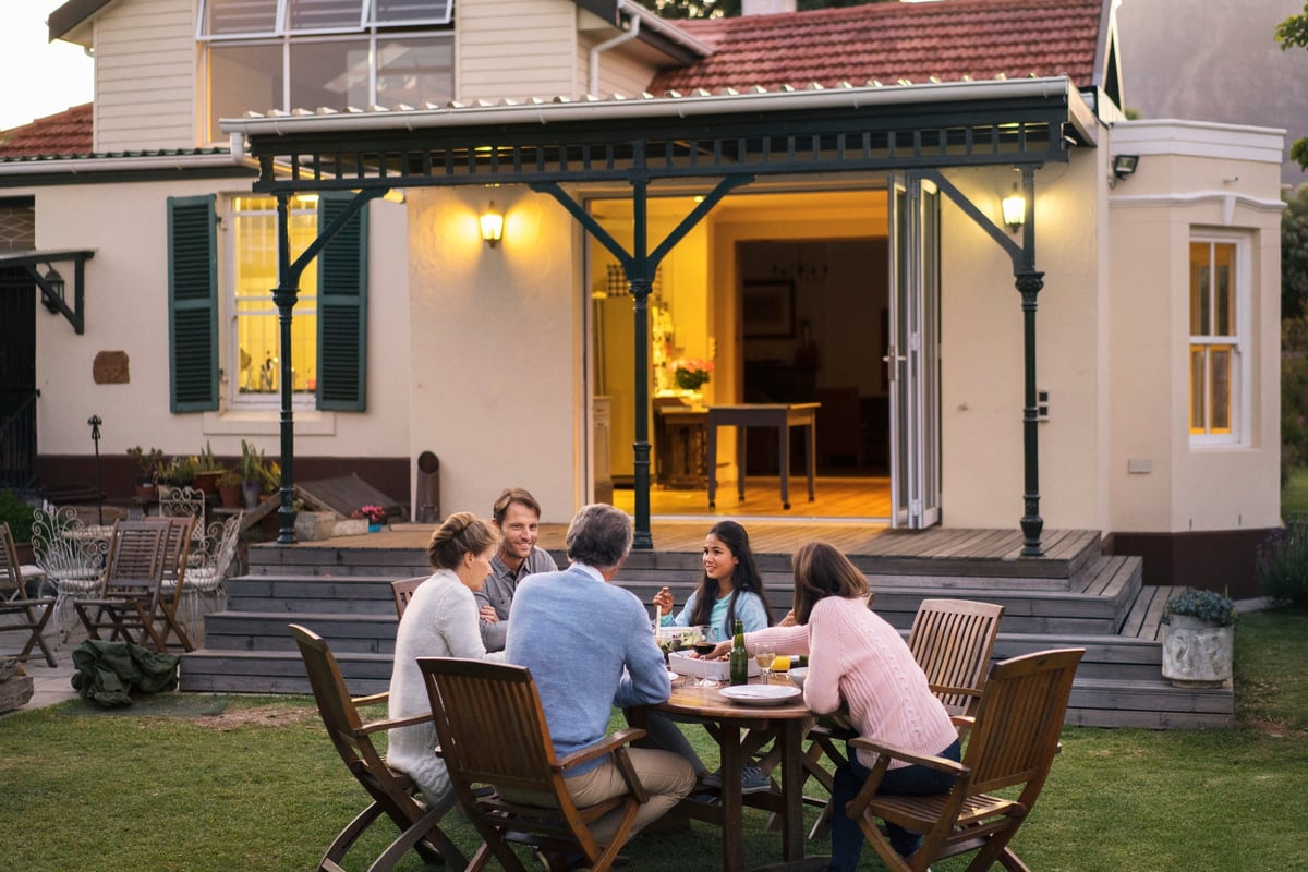 A family of five eating dinner at a backyard patio table.
