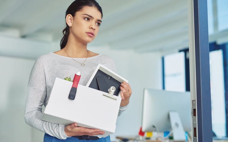 A young woman who has just quit her job comes out of the office with a box of her things.