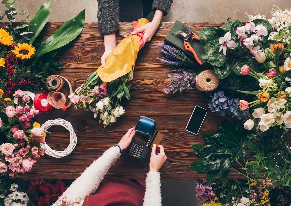 A florist swiping a credit card between bunches of flowers.