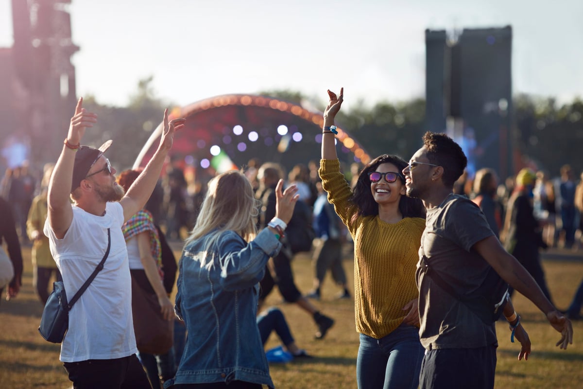Group of friends dancing in the crowd as they walk on stage at a music festival.