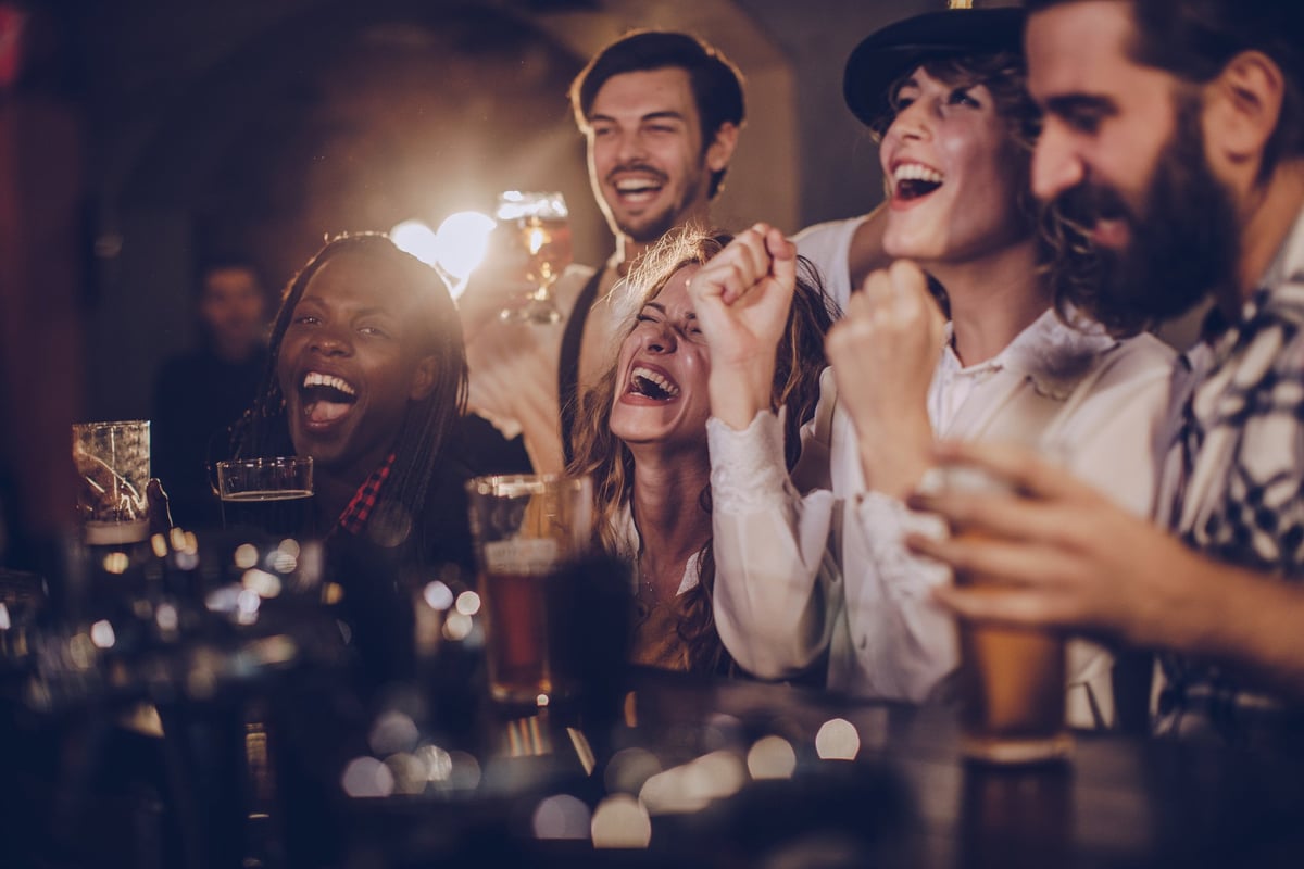 A group of friends laughing over drinks at a bar.