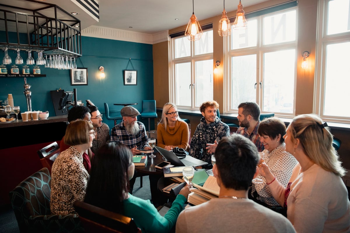 A group of people sitting in a circle of chairs having a social meeting at a restaurant.