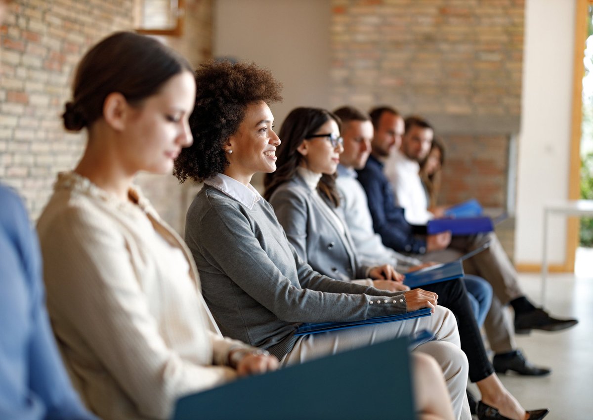 A group of people sit and wait for a job interview.
