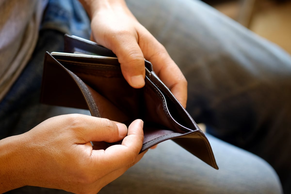 Hands open up a wallet showing that the inside is empty.