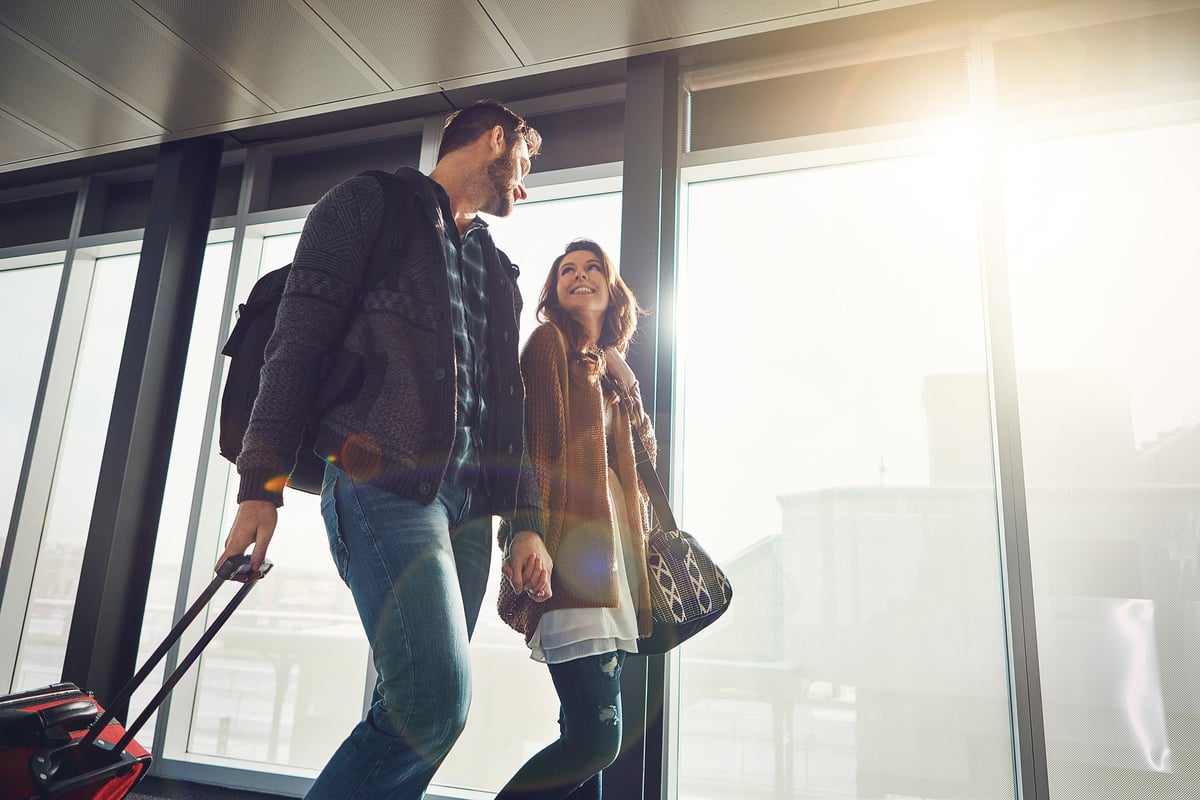 A happy couple holding hands while walking in an airport.