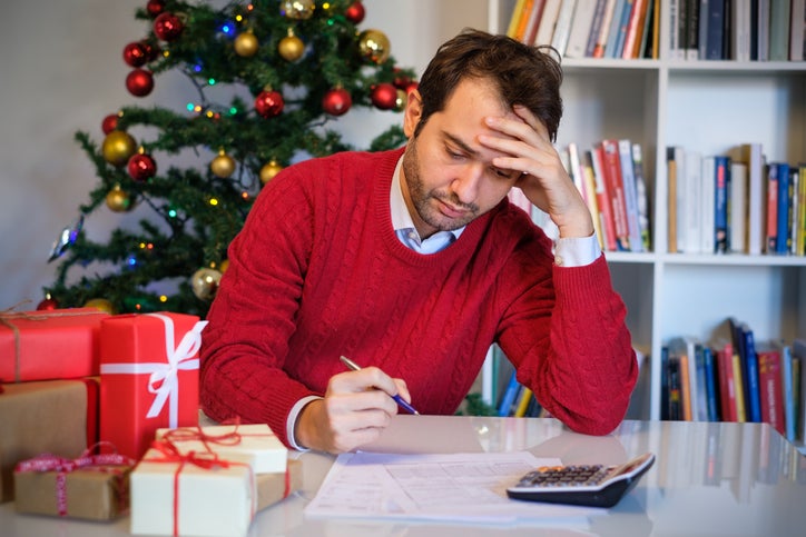 A man looks at bills beside a stack of presents.