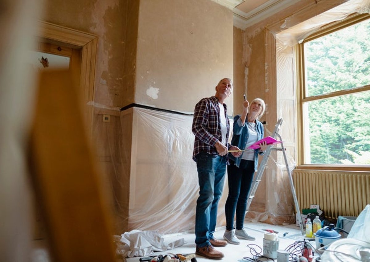 A man and woman looking around a room that's being renovated.
