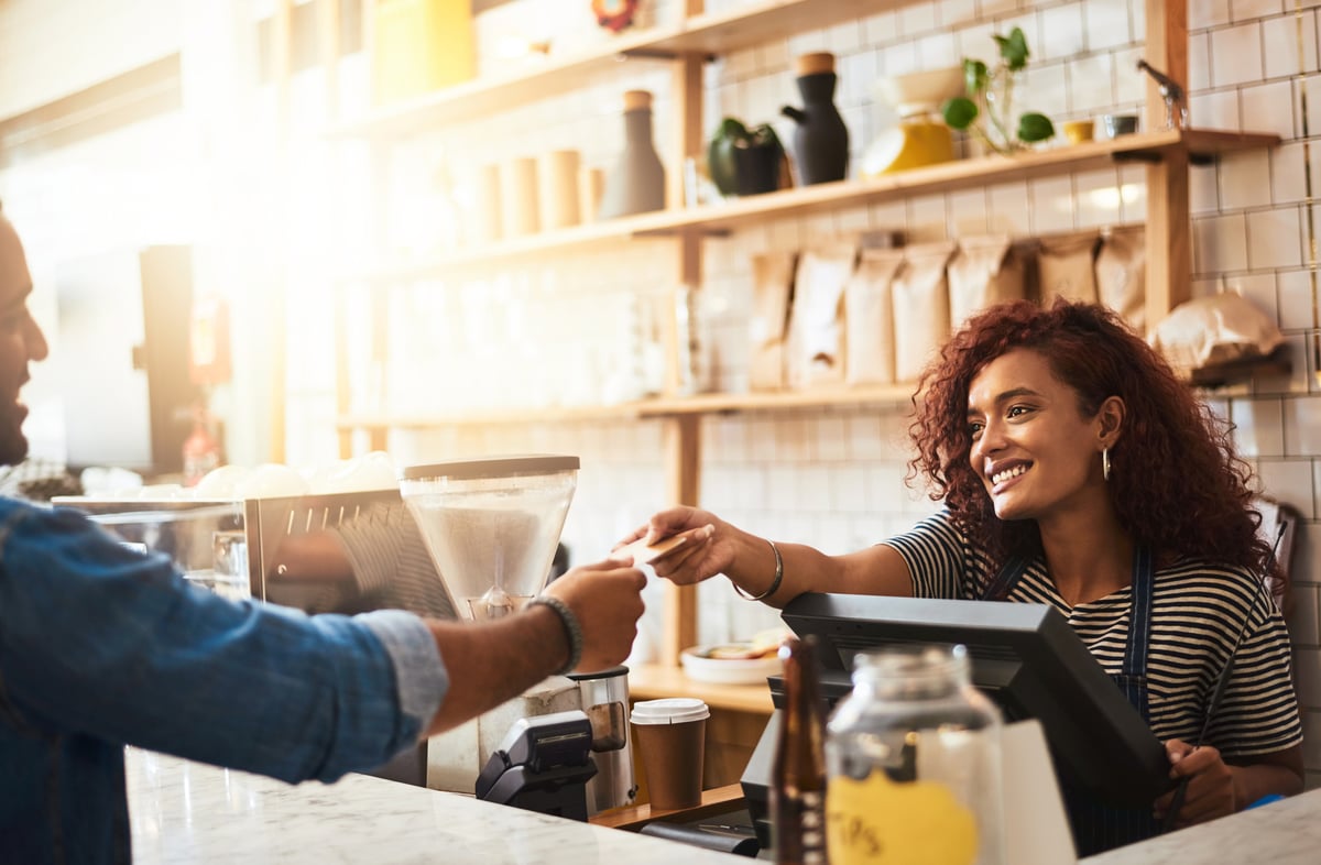 A man handing his credit card to the cashier at a coffeeshop.