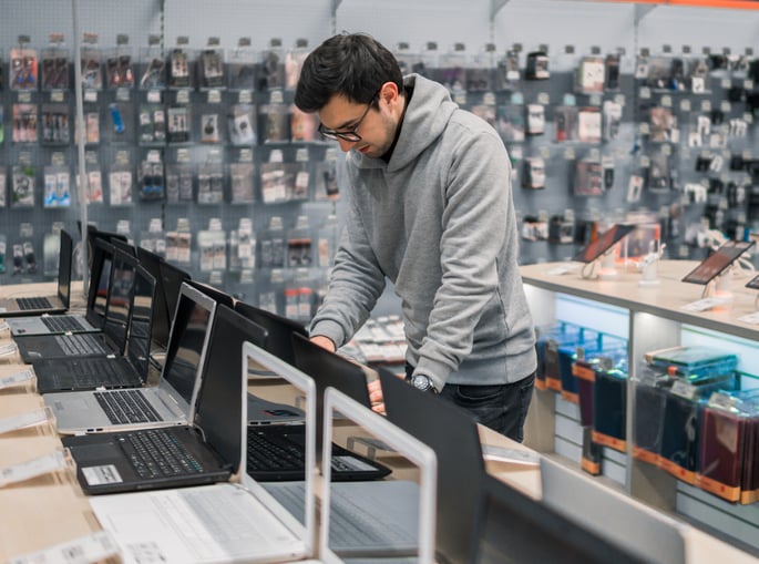 A man testing out laptops in an electronics store.