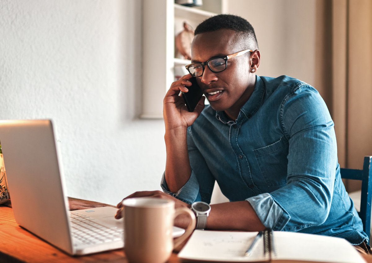 A man on a phone call while sitting in front of his laptop.