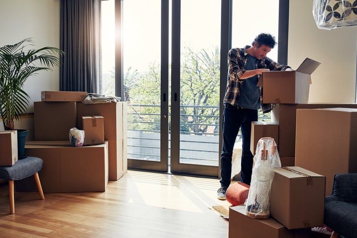 A man unpacking moving boxes in his new home.