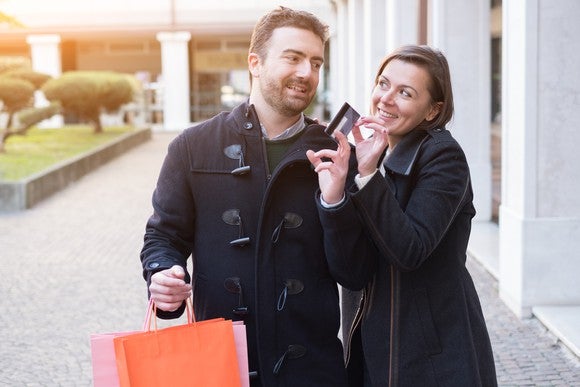 young couple shopping with both hands on a credit card