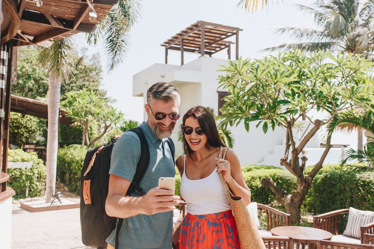 mature man and woman taking a selfie in front of a hotel and palm trees