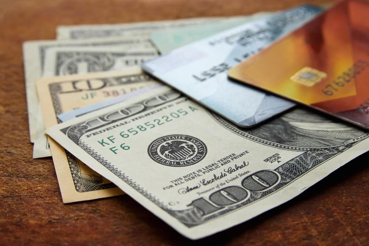 Two credit cards sitting on top of various American dollars.