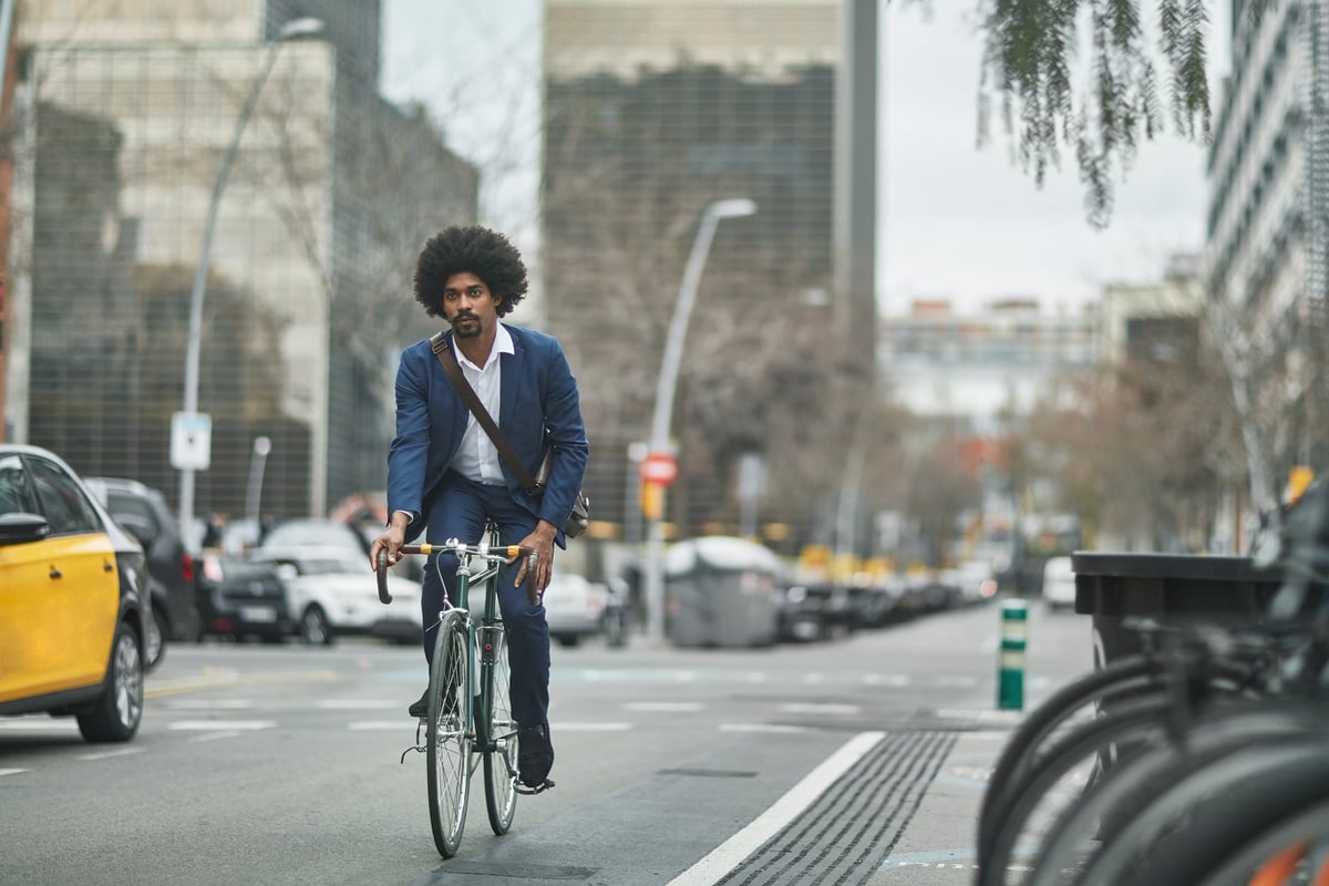 A person wearing business clothes and riding a bike on a city street.