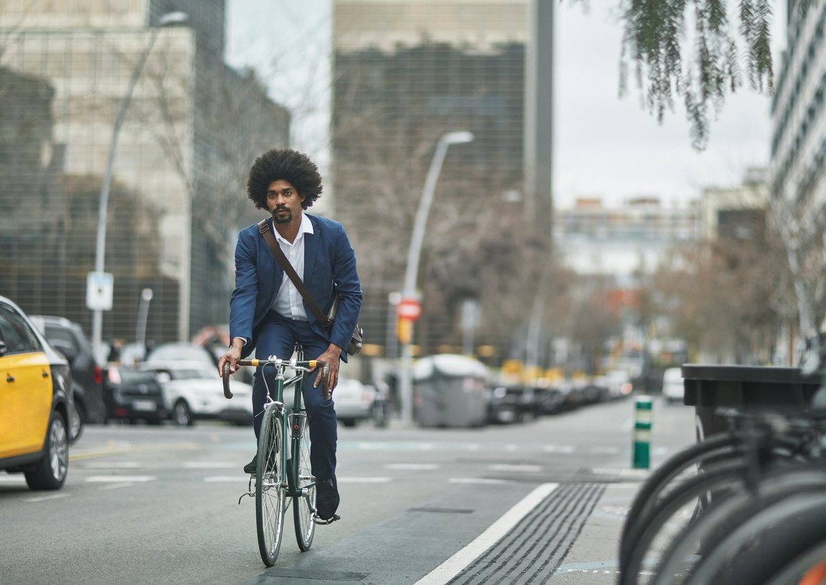 A person wearing business clothes and riding a bike on a city street.