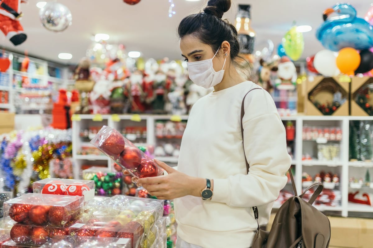 A person wearing a medical mask shopping for holiday decorations in a store.