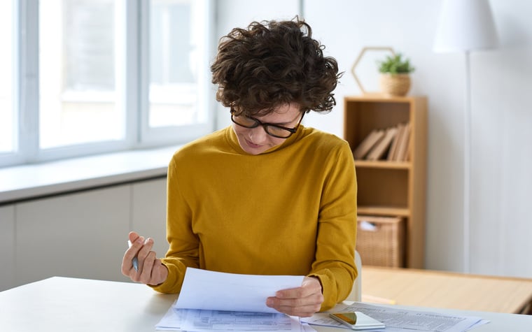 A person sitting at a desk and filling out paperwork.