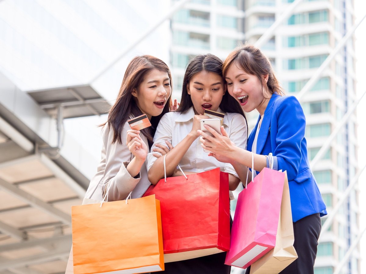 three girls holding shopping bags and credit cards taking a selfie