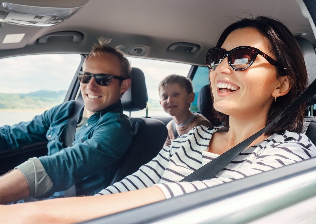 Family on a road trip wearing sunglasses and windows down.
